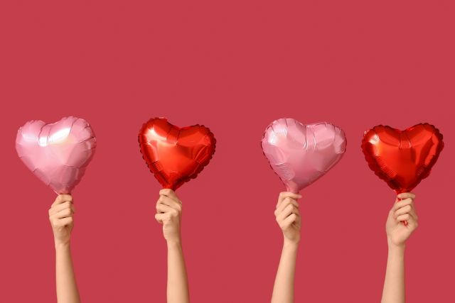 赤とピンクのハートの風船を持つ女性