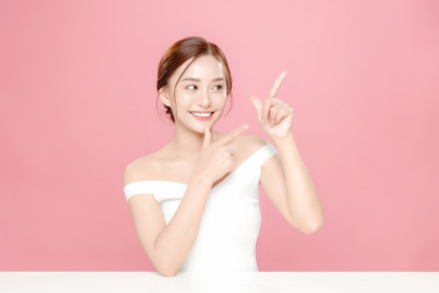 横を指さす女性